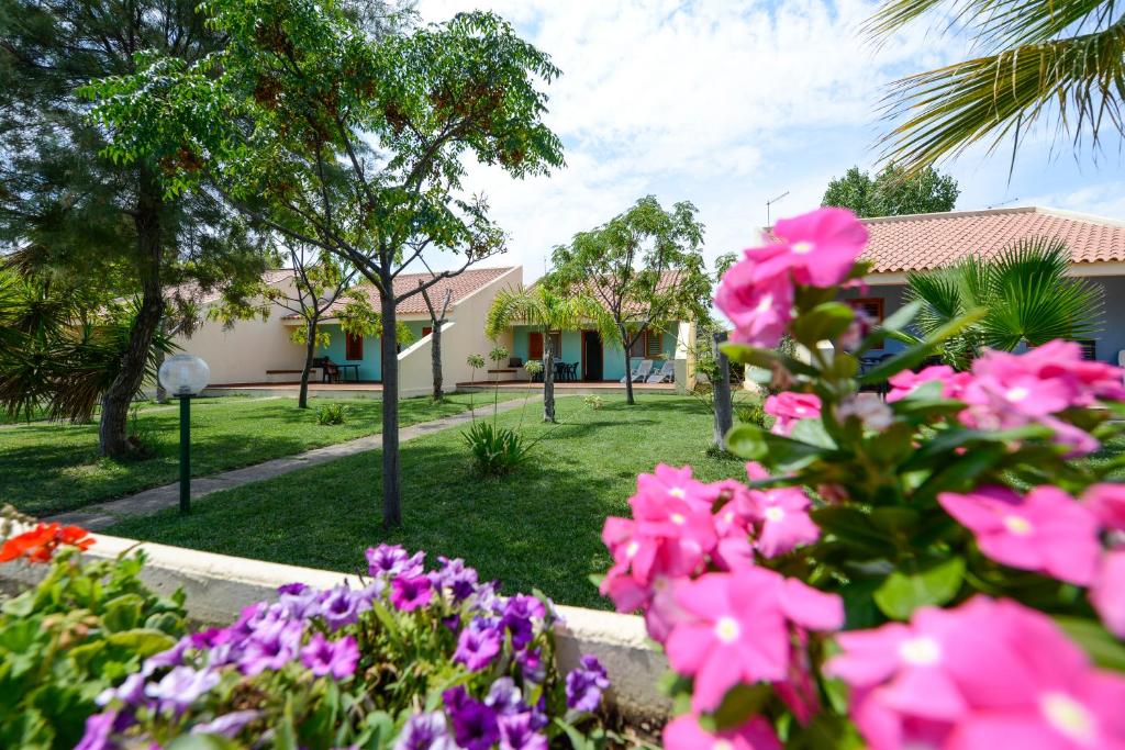 un giardino con fiori rosa di fronte a una casa di Villaggio Le Palatine a Metaponto