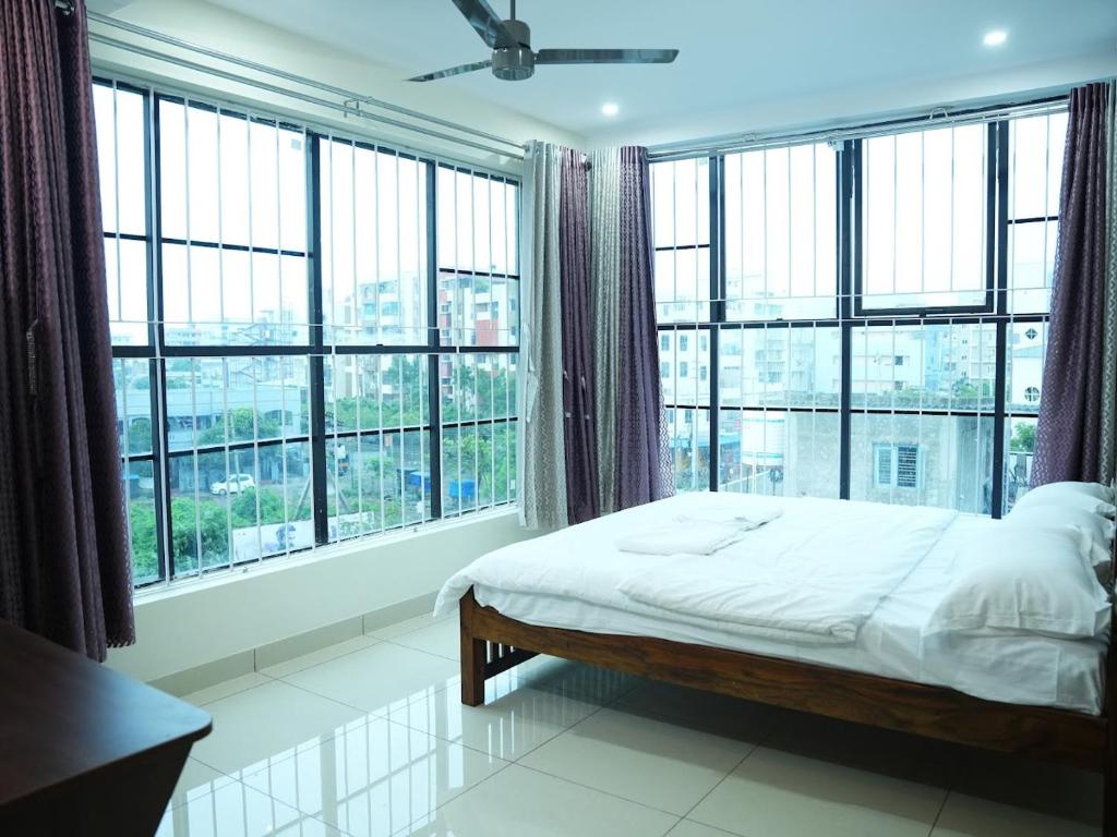 a bed in a room with large windows at Hotel Brinda in Kākināda