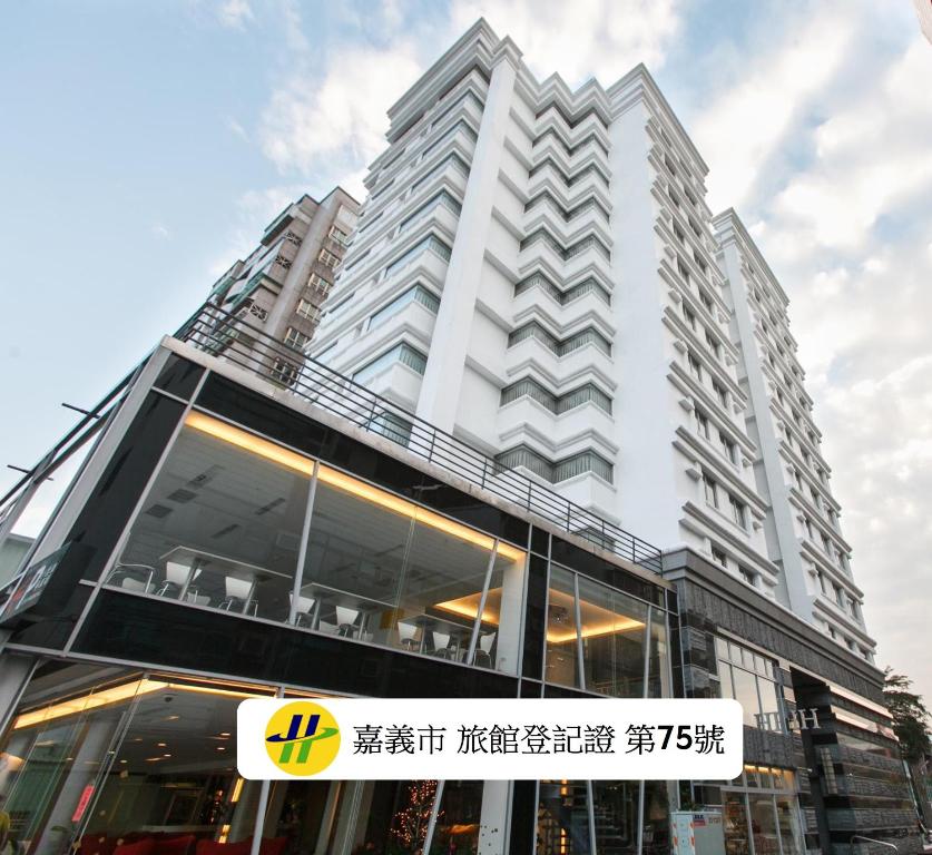 a tall white building with a sign in front of it at HOTEL HI - Xinmin in Chiayi City