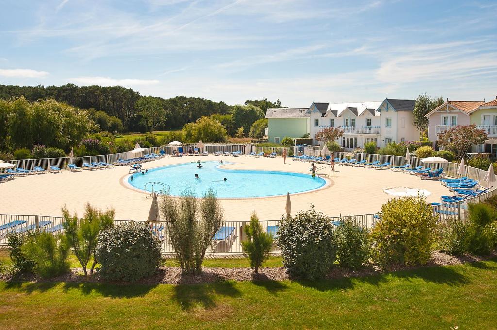 uma grande piscina com cadeiras e pessoas nela em Residence Port Bourgenay - maeva Home em Talmont