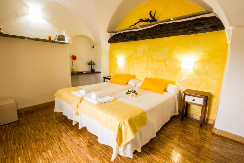 1 dormitorio con 1 cama grande y pared amarilla en La Posada de Grimaldo, en Grimaldo