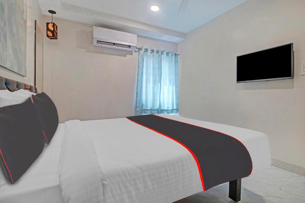 a bedroom with a white bed and a television at Super Collection O Halcyon SS Grand in Hyderabad