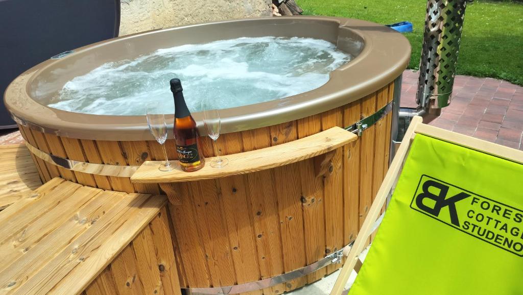 a hot tub with a bottle of beer in it at Gozdna koča Studeno in Kočevje