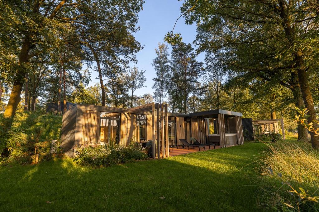 a cabin in the woods with a green lawn at Zicht op Twente - Spa lodges in Markelo