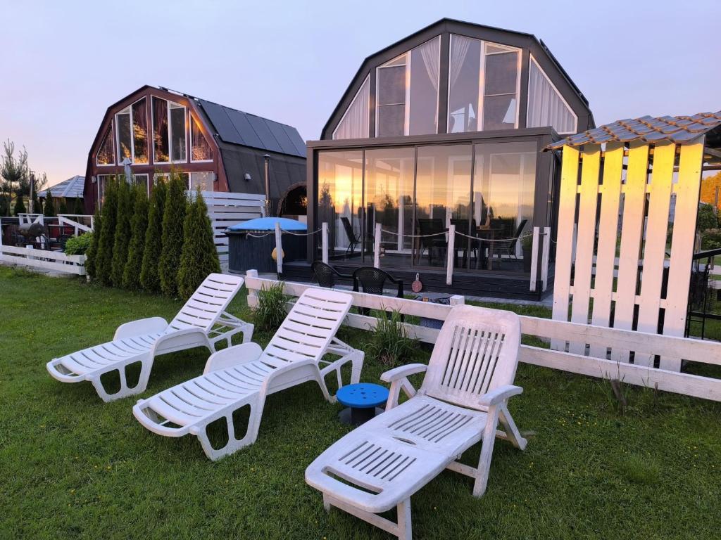 a group of white chairs in front of a house at Saulėlydis in Dreverna
