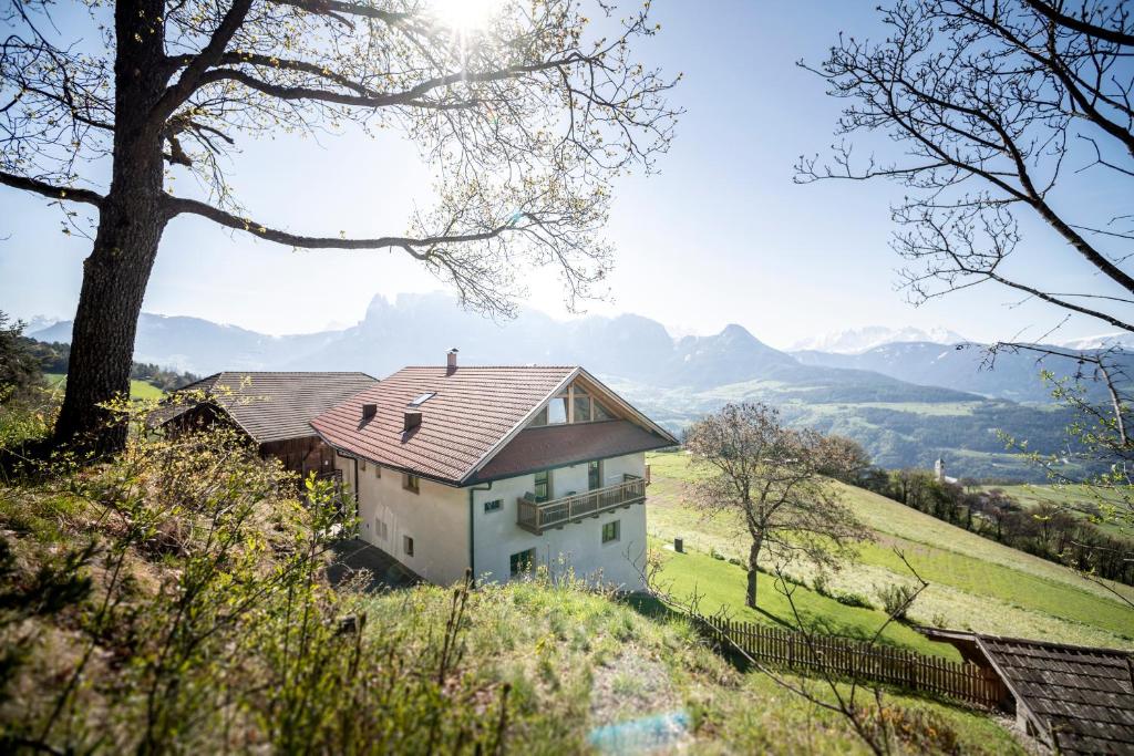 a house on a hill with mountains in the background at Obersteinerhof in Collalbo