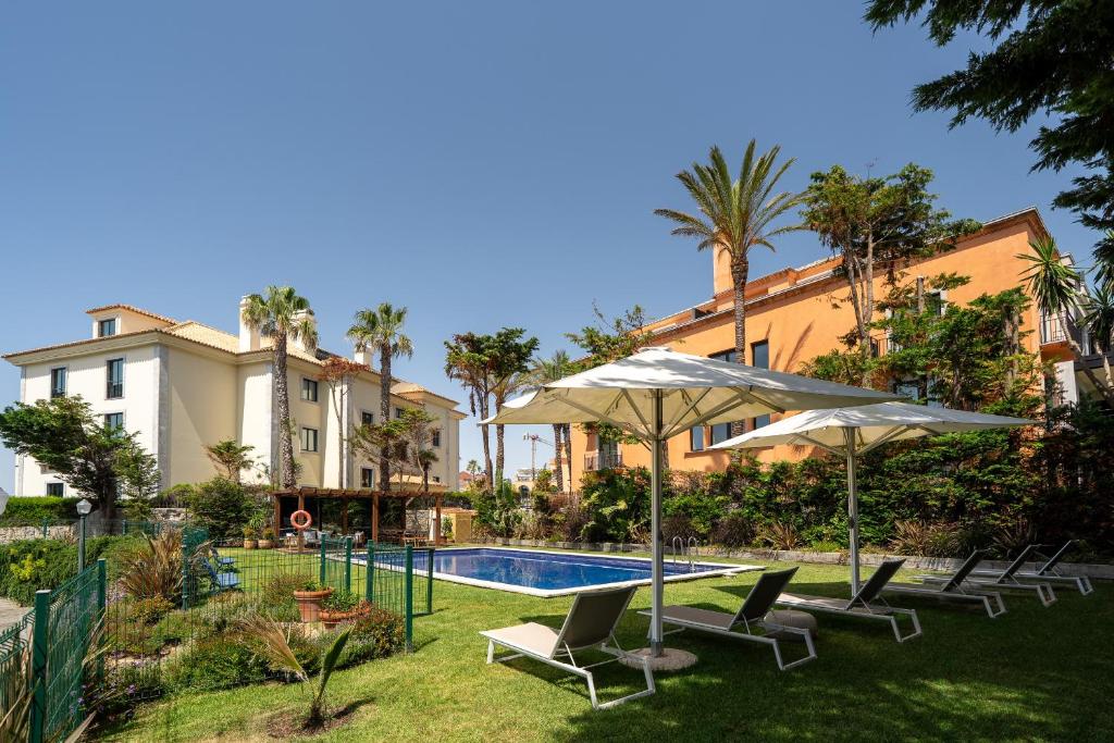 a resort with a swimming pool with chairs and umbrellas at Blissful Seafront in Cascais