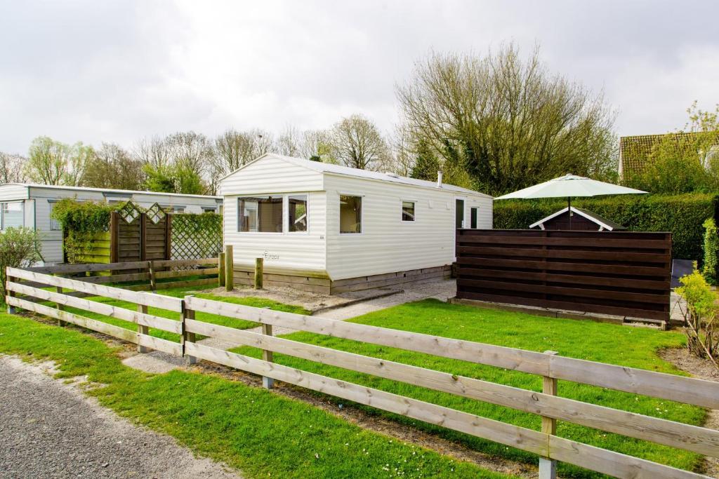 a white tiny house in a yard with a fence at RBR 166 - Beach Resort Kamperland in Kamperland