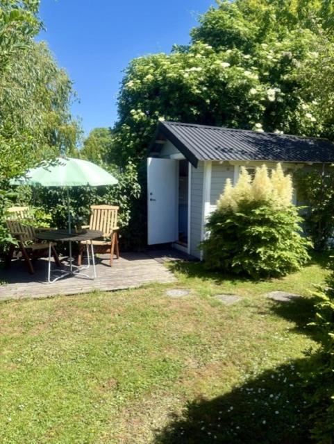 a small shed with a table and an umbrella at Strandnära Stuga Saga in Visby