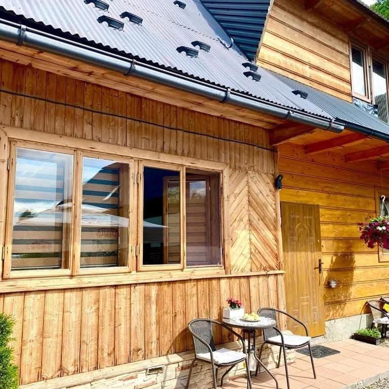 a wooden house with a table and chairs on a patio at Apartament i Pokoje u Moniki in Witów