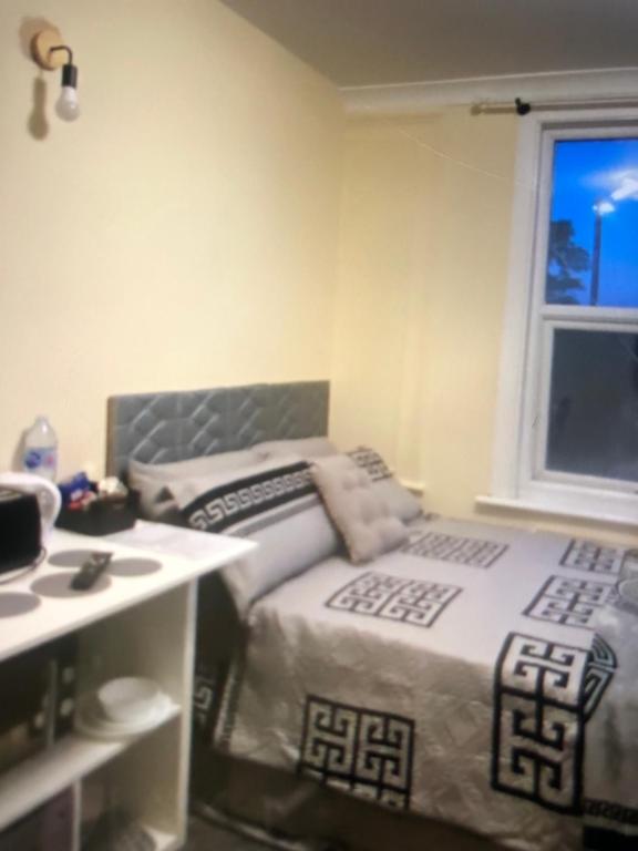 a bedroom with two beds and a table and a window at Neil2 in London