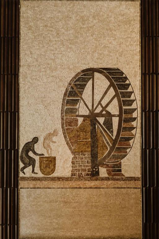 a mural on the side of a building with a wheel and two men fighting at The Noria Hotel in Arsuz
