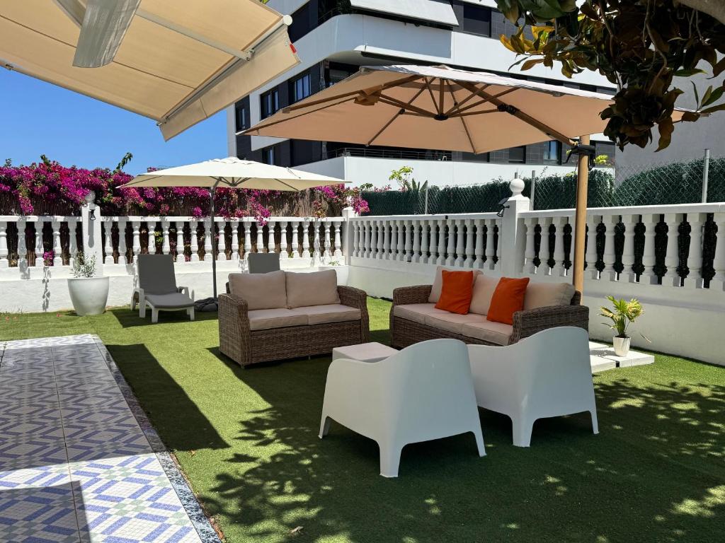 a patio with couches and chairs and an umbrella at VillaBrisaeta, villa costera a un paso de todo. in Benicàssim