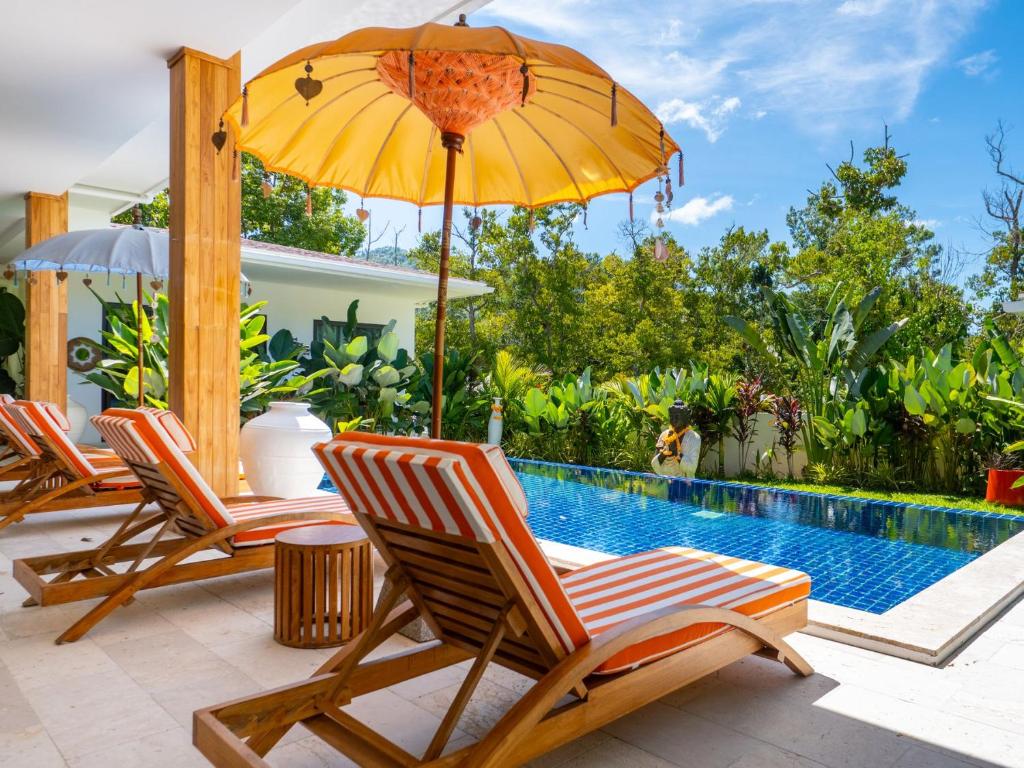 a group of chairs and an umbrella next to a pool at Enchanting Villa Namaste 3Br Private Pool & Garden in Nathon Bay