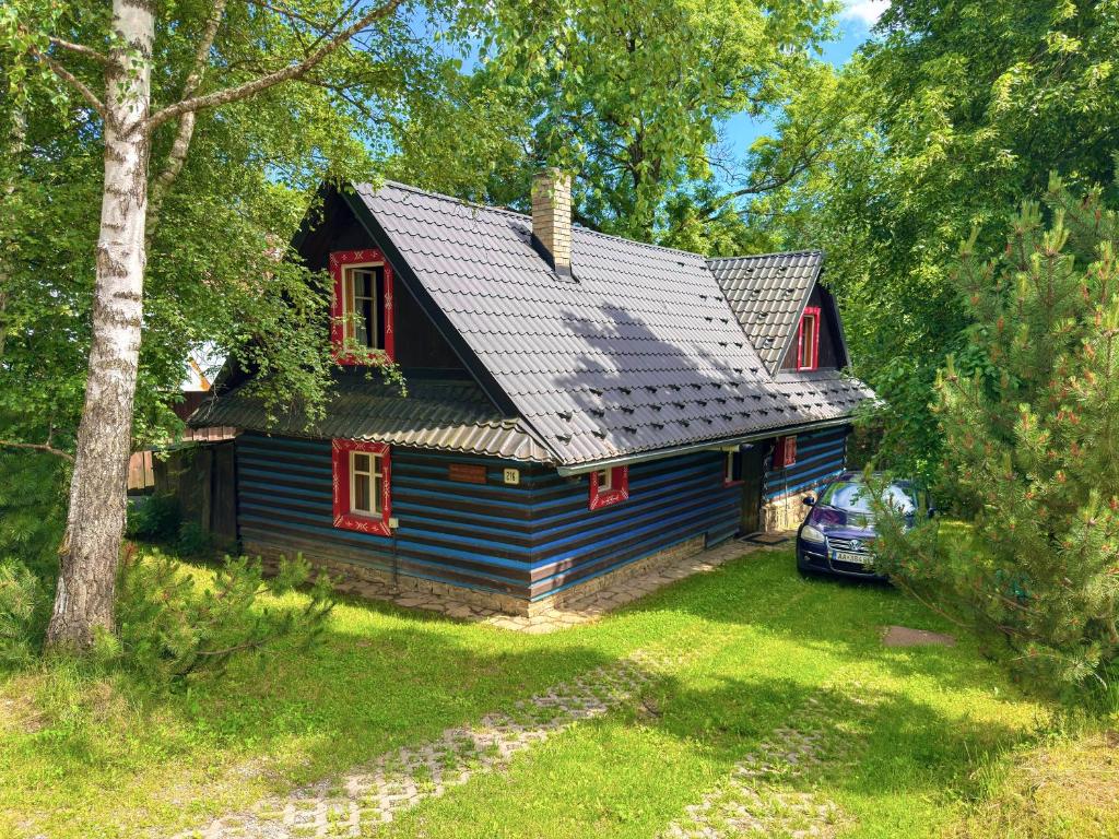 a blue house with red windows in a yard at Chalupa Jaseň in Ždiar