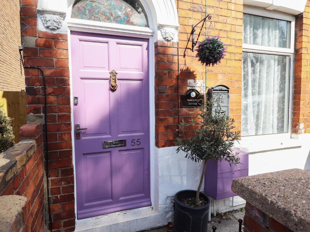 a purple door on the side of a brick building at Pankhurst Cottage in Louth