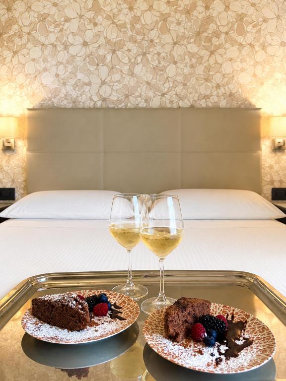 two cakes and wine glasses on a tray with a bed at Hotel Parigi 2 & Spa in Dalmine