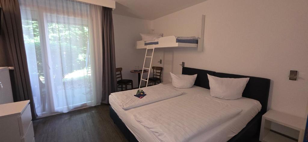 a small bedroom with a bed with white sheets and a window at Aparthotel Höper in Oyten
