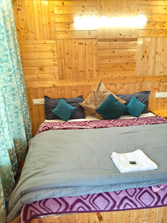 a bed in a room with wooden walls at Radhakrishna Homestay in Kulu