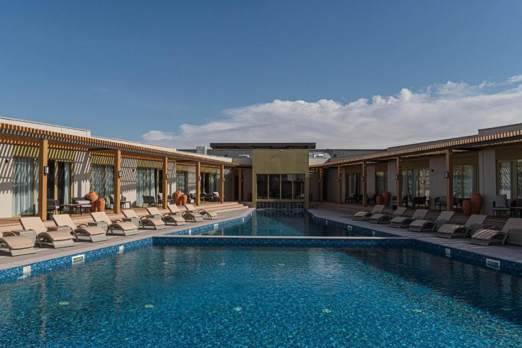 a swimming pool with lounge chairs and a building at Nammu Spa and Wellness in Dubun