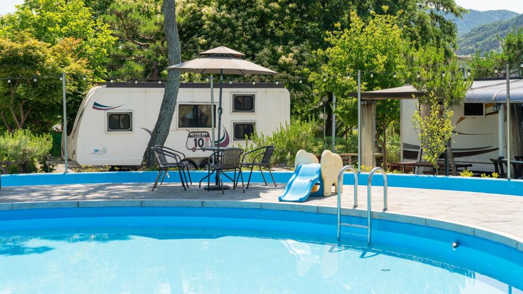 a pool with a table and chairs and a caravan at Gapeyong Donghwa Caravan in Gapyeong