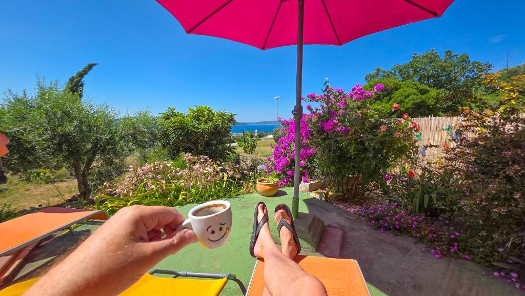 a person holding a cup of coffee and an umbrella at Mendy Sea View Apartment in Kaštela