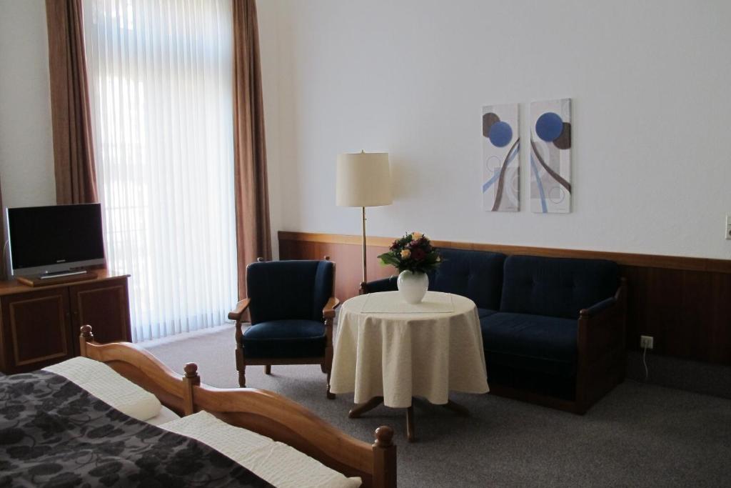 a room with a couch and a table and a tv at Hotel Anlage Heidelberg in Heidelberg