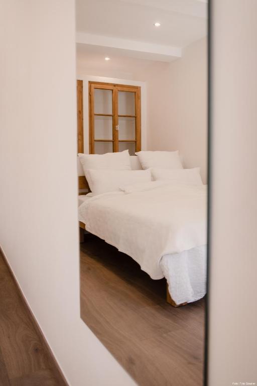 a bedroom with a bed with white sheets and a mirror at Haus Auf der Zinn in Beilstein