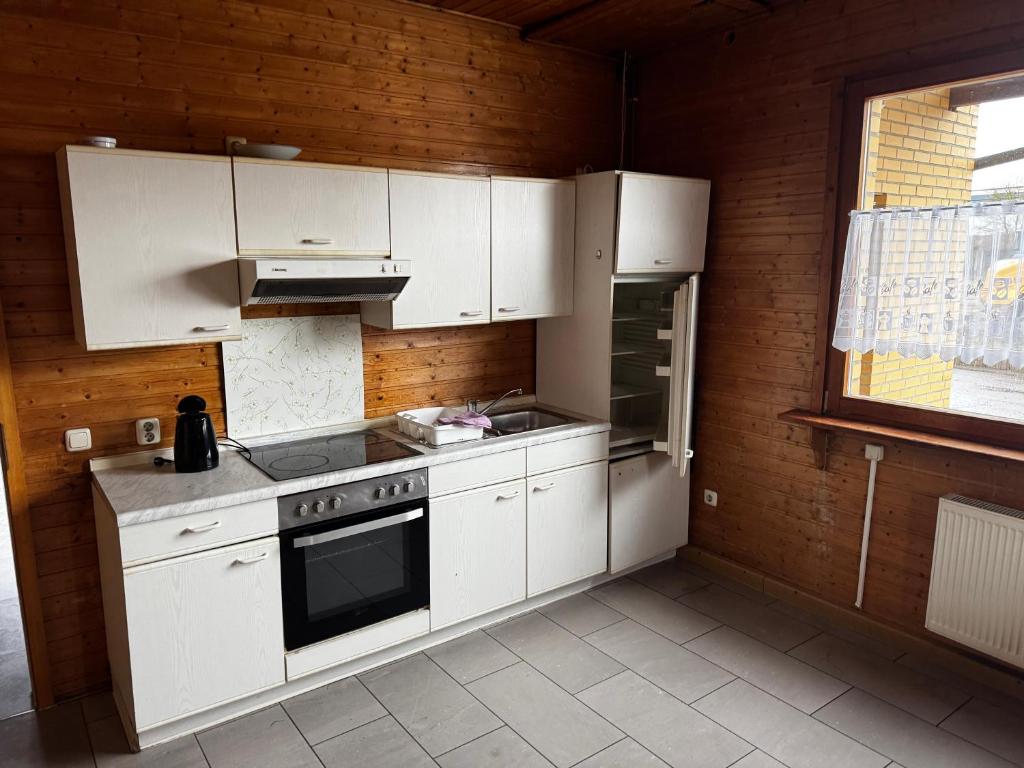 a kitchen with white cabinets and a stove and a window at Monteurzimmer Drei Gleichen in Günthersleben