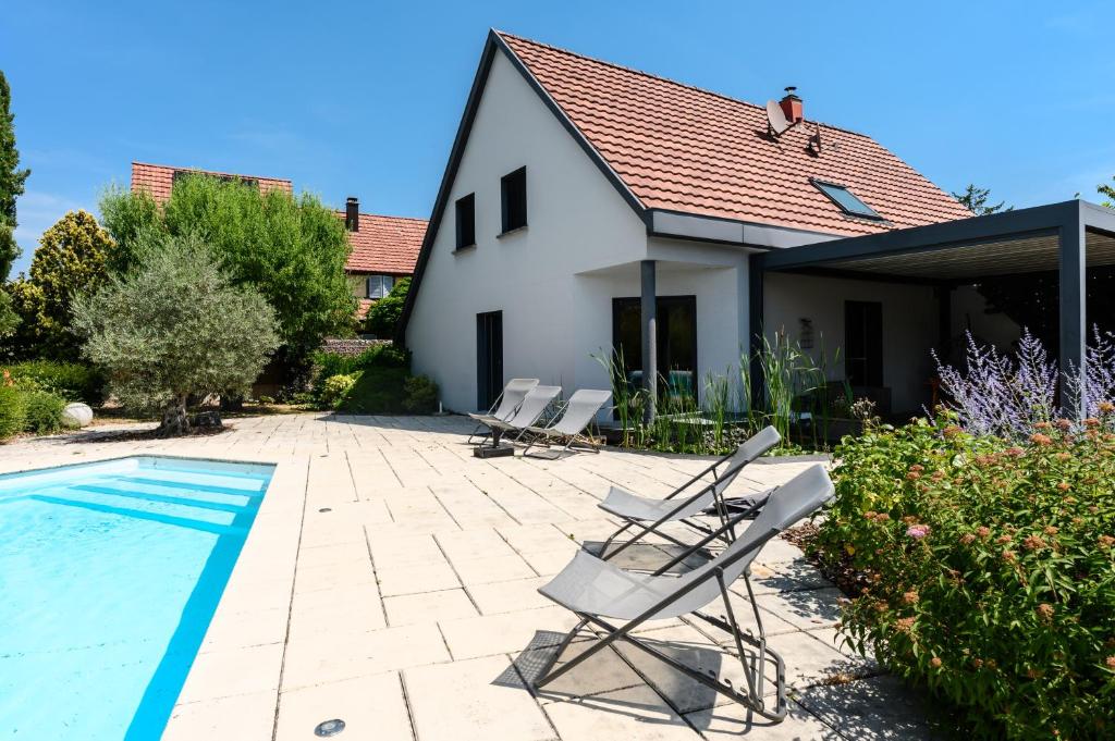 a group of chairs sitting next to a swimming pool at Le Vogelgarten in Zellenberg