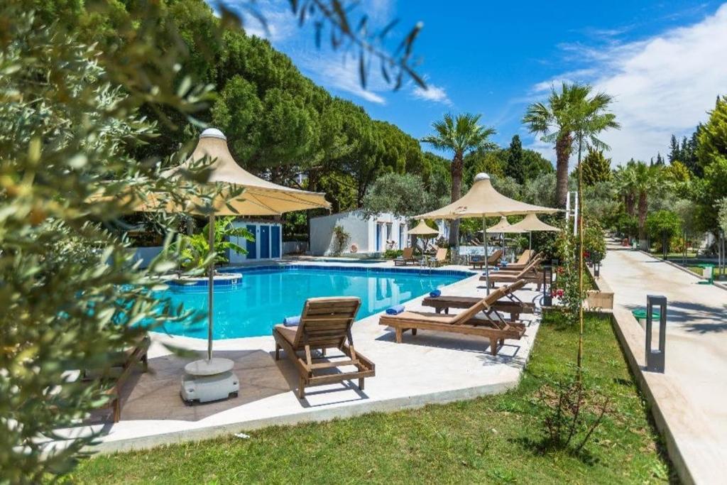 a swimming pool with lounge chairs and umbrellas at Adella Garden Marina Hotel in Güvercin Adası
