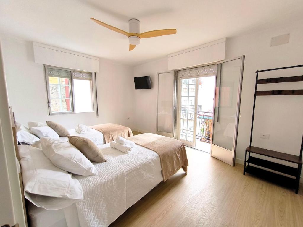 a white bedroom with a bed and a ceiling fan at Casa Gaia Centrally located accommodation with spacious rooms in Redondela