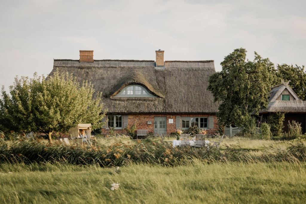 an old house with a gambrel roof in a field at Ferienhaus Gut Glück in Lancken-Granitz