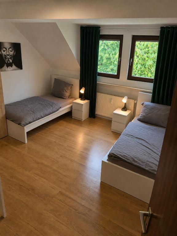 a bedroom with two beds and two windows at Stay Offenbach in Bürgel
