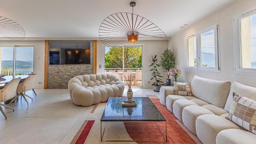 a living room with couches and a table at Villa Panoramique - Lac du Bourget in Bourdeau