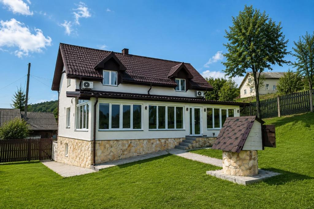a white house with a brown roof at Вілла Смерекова хата in Kelechin