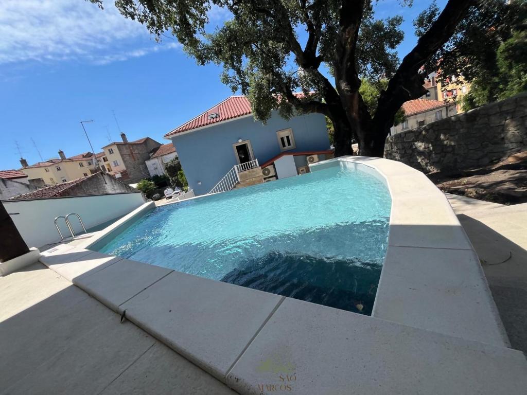 a swimming pool in front of a house at Quintal de São Marcos in Castelo Branco