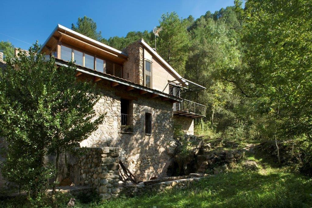 a house on the side of a hill with trees at La Farga de la Muga in Sant Llorenç de la Muga