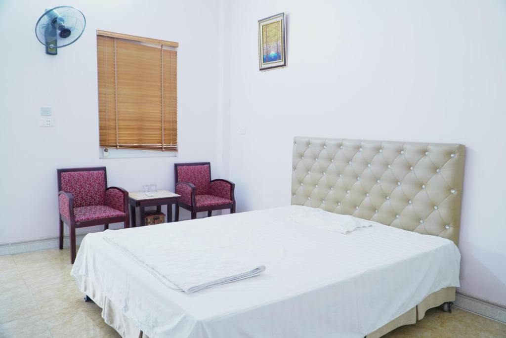 a bedroom with a large bed and two chairs at Ngày Mới Hotel in Nghĩa Lộ