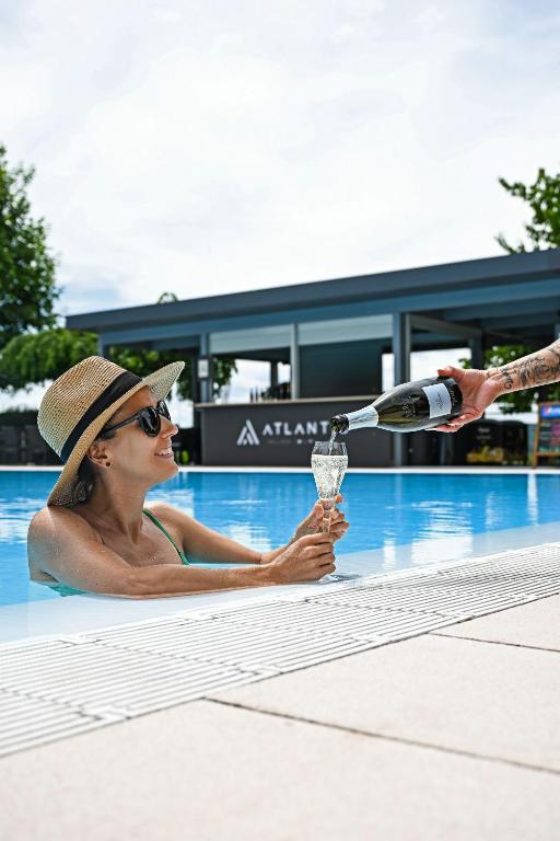 Eine Frau in einem Schwimmbecken, die ein Glas Wein hält in der Unterkunft Hotel Atlantis in Brünn