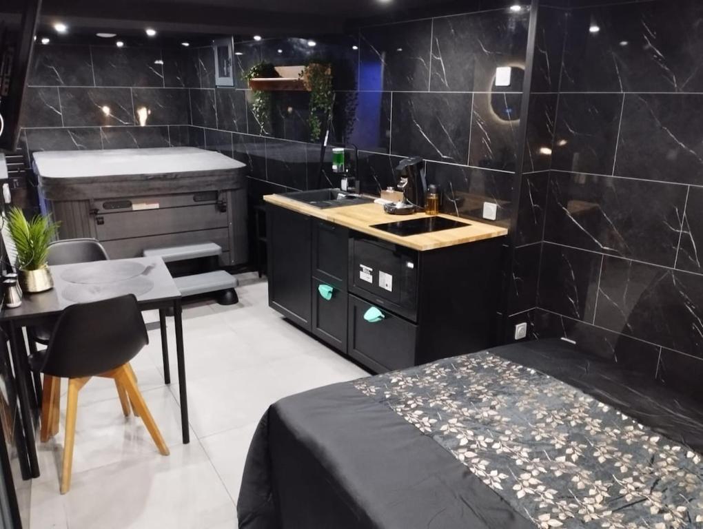 a room with a bed and a kitchen with a sink at L'Échappée Romantique & Spa Privatif in Foix