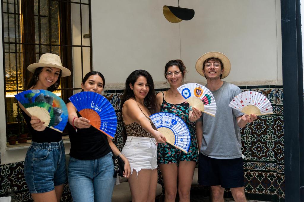 a group of people holding up paper umbrellas at Black Swan Hostel Granada in Granada
