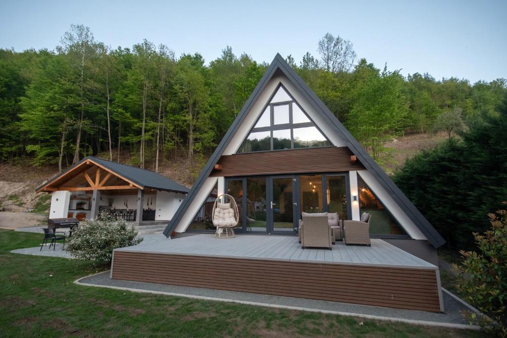 a house with a large deck with two chairs at Cabana Casa Luca in Rănuşa