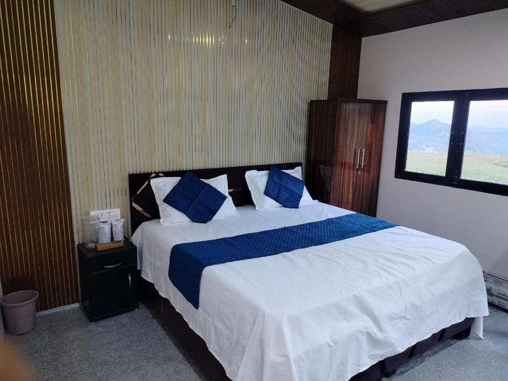 a bedroom with a large bed with blue pillows at Pahadi aangan in Bhīm Tāl