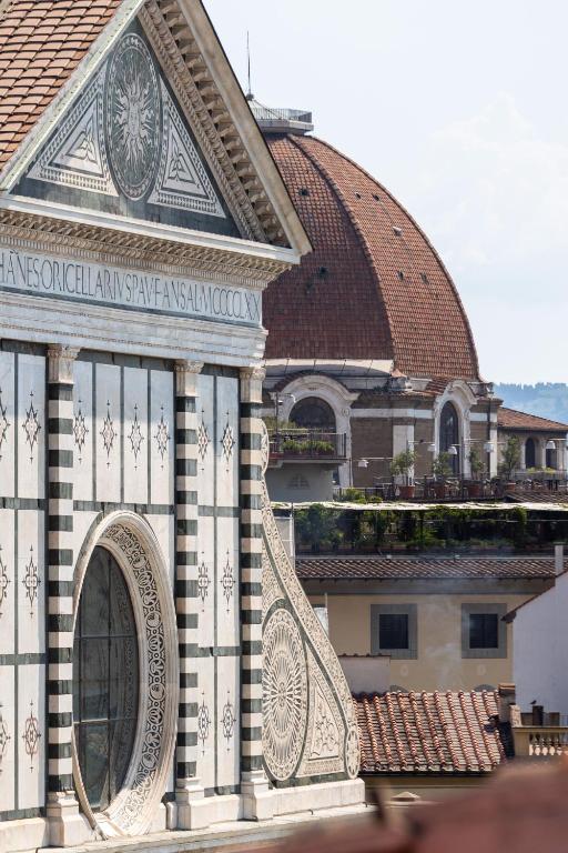 a building with a tiled roof with a clock tower at Bohemian Palace Florence in Florence