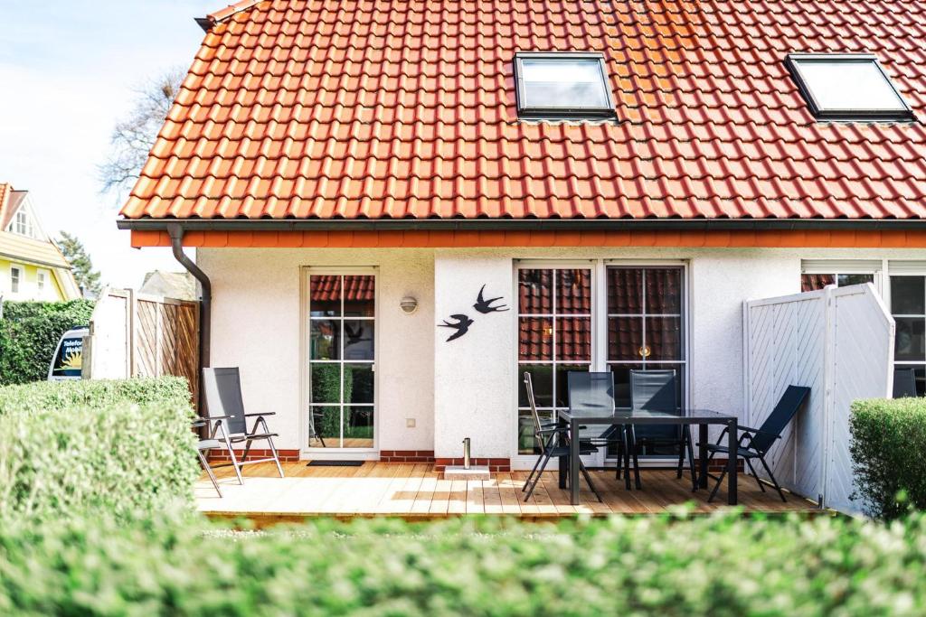 a house with an orange roof with a table and chairs at Rauchschwalbe in Zingst