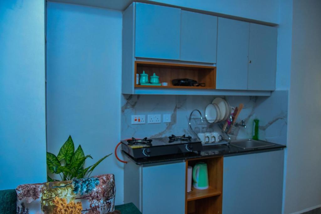 a kitchen with blue cabinets and a sink and a chair at Kiesth Whiskaway in Kiambu