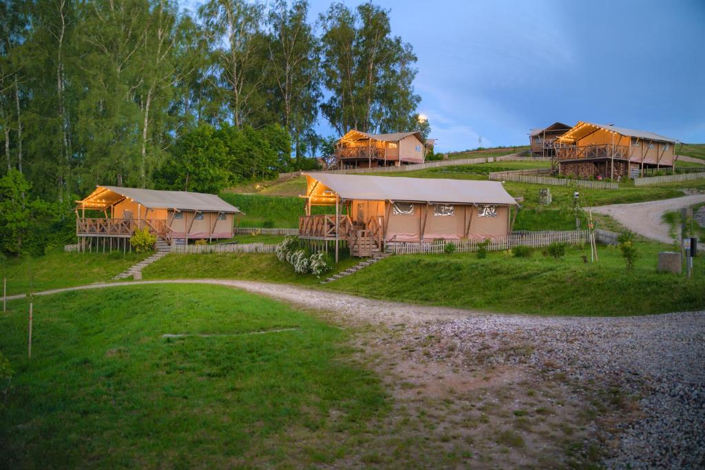 a group of houses on a hill with a dirt road at "Wioska Wakacyjna Glamila" Mazury, nad jeziorem, podgrzewany basen, Glamping i domki rodzinne in Sterławki Wielkie