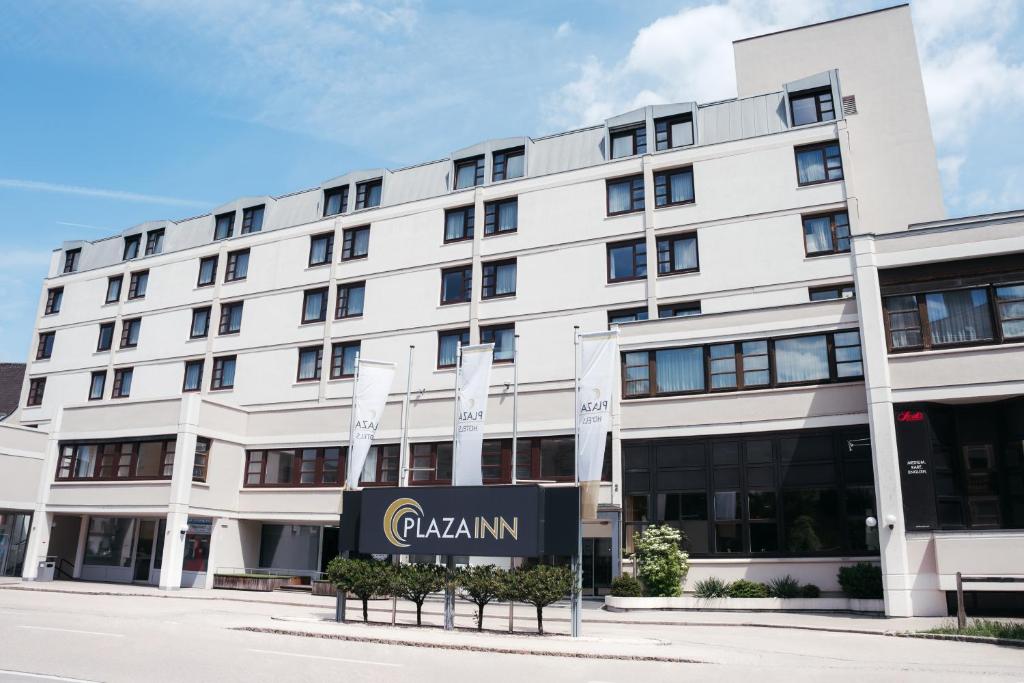 ein weißes Gebäude mit einem Schild davor in der Unterkunft PLAZA INN Wels in Wels