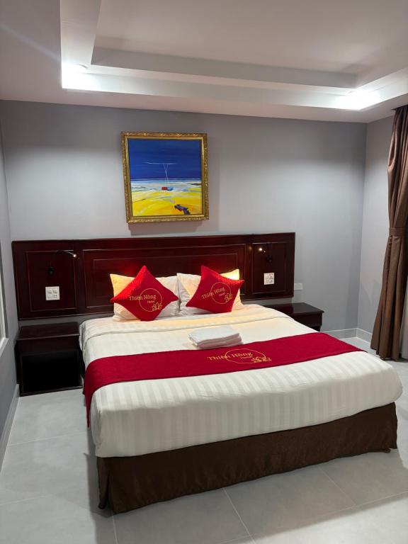 a bedroom with a large bed with red pillows at Hotel Thiên Hồng in Phú Quốc
